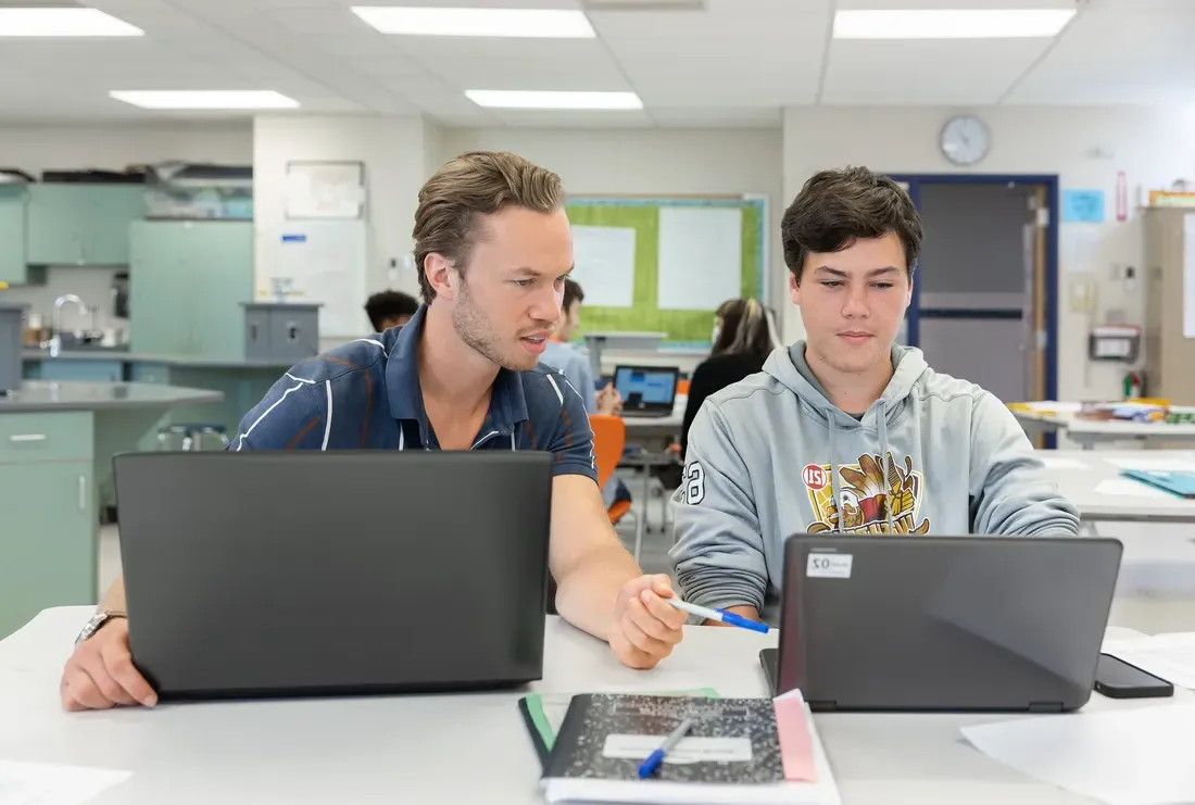 Aspiring teacher helping student on computer.
